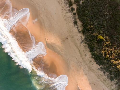 Aerial view of breaking wave washing on a sandy Beach - Australian Stock Image