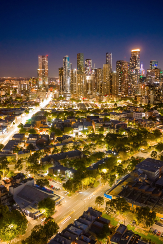 Aerial view of bright lights of a city skyline and surrounding suburbs at twilight - Australian Stock Image