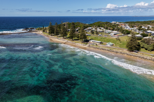 Aerial view of Brooms Head Beach and rocky headland, showing the sandy shoreline, Pacific Ocean - Australian Stock Image