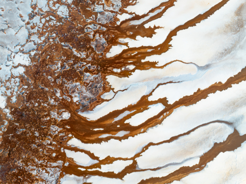 Aerial view of brown groundwater making patterns in a salt lake - Australian Stock Image