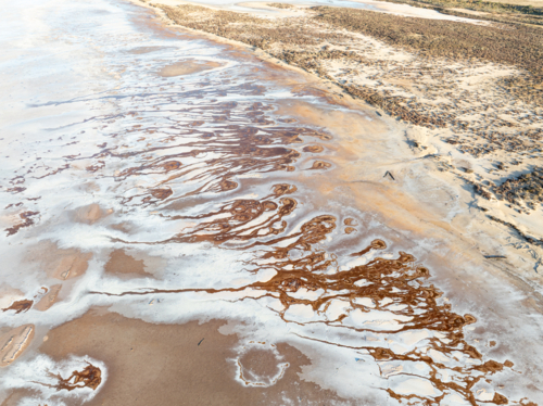 Aerial view of brown groundwater making patterns in a salt lake - Australian Stock Image
