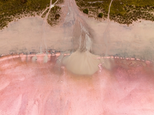 Aerial view of brown silt draining on to a pink salt lake