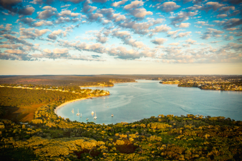 Aerial view of coastal bay with sailboats, houses, and sunset glow over Port Hacking and Bundeena. - Australian Stock Image