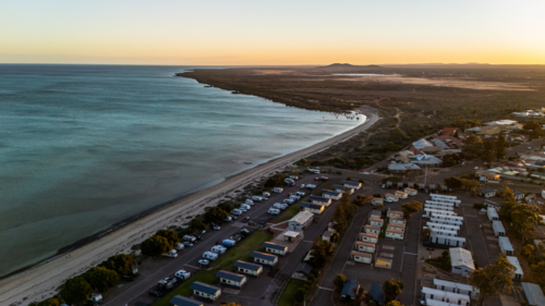 Aerial view of coastal caravan park with cabins at sunset - Australian Stock Image