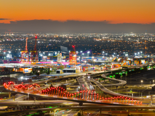Aerial view of coloured lighting on freeways and bridges in a major city at twilight - Australian Stock Image