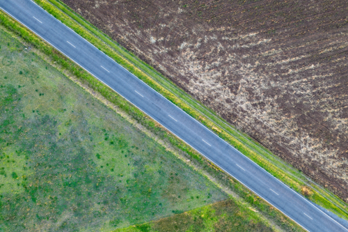 Aerial view of country road passing through agricultural fields. Scenic rural landscape. - Australian Stock Image