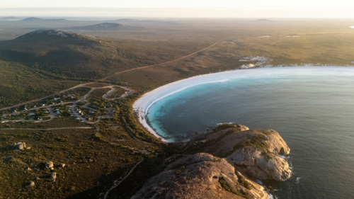 Aerial view of crescent-shaped beach at sunset - Australian Stock Image
