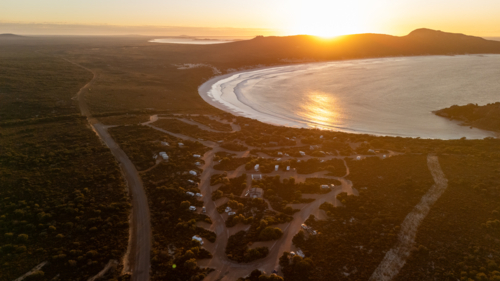 Aerial view of crescent-shaped beach at sunset - Australian Stock Image