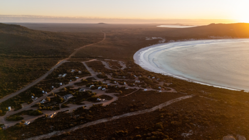 Aerial view of crescent-shaped beach at sunset - Australian Stock Image