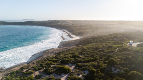 Aerial view of crescent-shaped beach with turquoise water - Australian Stock Image