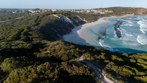 Aerial view of crescent-shaped beach with turquoise water - Australian Stock Image