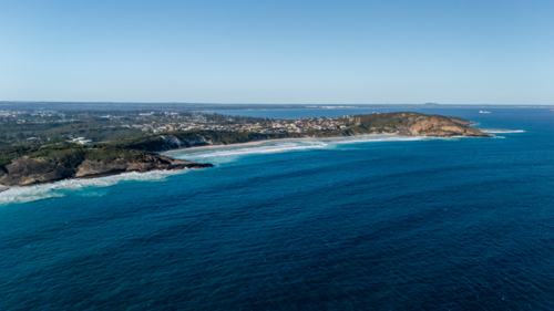 Aerial view of crescent-shaped beach with turquoise water - Australian Stock Image