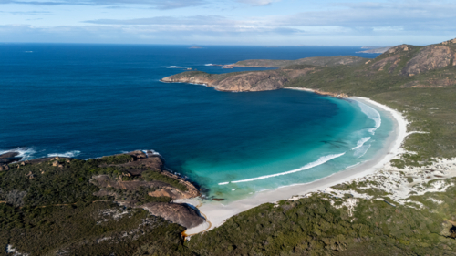 Aerial view of crescent-shaped beach with turquoise water. - Australian Stock Image