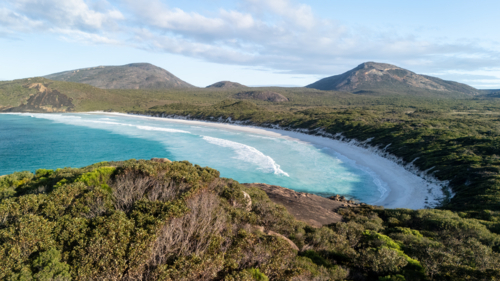 Aerial view of crescent-shaped beach with turquoise water. - Australian Stock Image