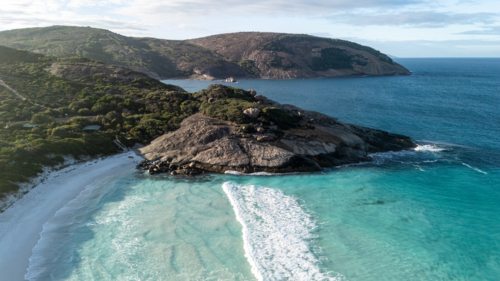Aerial view of crescent-shaped beach with turquoise water - Australian Stock Image
