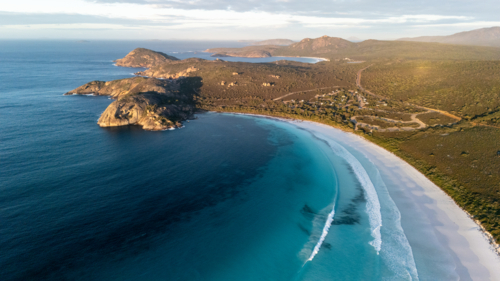 Aerial view of crescent-shaped beach with turquoise water - Australian Stock Image