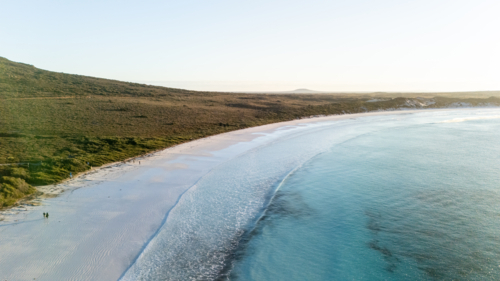 Aerial view of crescent-shaped beach with turquoise water. - Australian Stock Image