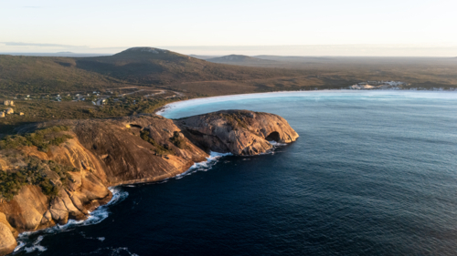 Aerial view of crescent-shaped beach with turquoise water - Australian Stock Image