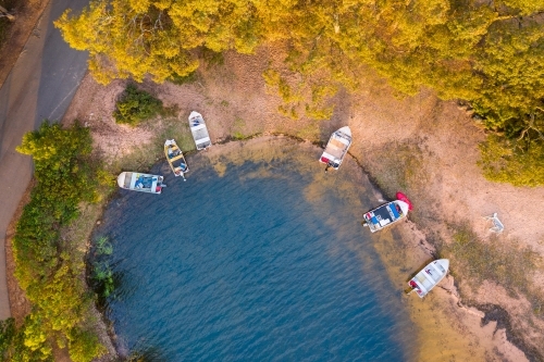 Aerial view of dinghies pulled ashore around the shoreline of a lake - Australian Stock Image