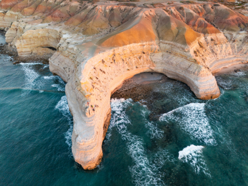 Aerial view of dramatic eroded cliff tops along a rugged coastline at sunset - Australian Stock Image