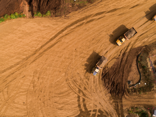 Aerial view of dump trucks transporting dirt around construction site for building bypass - Australian Stock Image