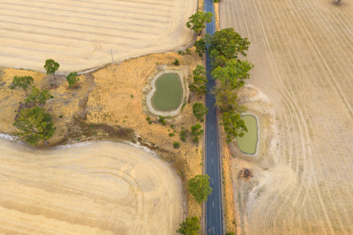 Aerial view of farm dams in dry paddocks along a country road - Australian Stock Image
