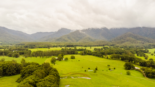 aerial view of green rolling hills and distant mountains - Australian Stock Image