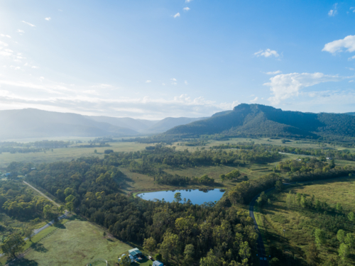 Aerial view of green rural landscape with dam and hills in Broke Hunter Valley bathed in light - Australian Stock Image