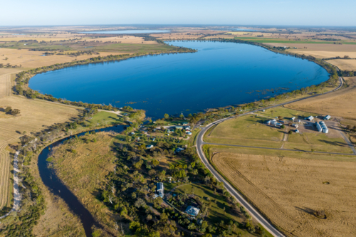 Aerial view of lake surrounded by farmland and rural settlement. - Australian Stock Image