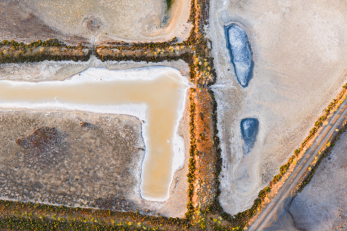 Aerial view of levee banks and colourful evaporation ponds at a coastal salt works - Australian Stock Image