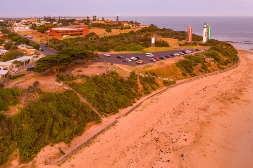 Aerial view of lighthouses and car park above a sandy beach at twilight