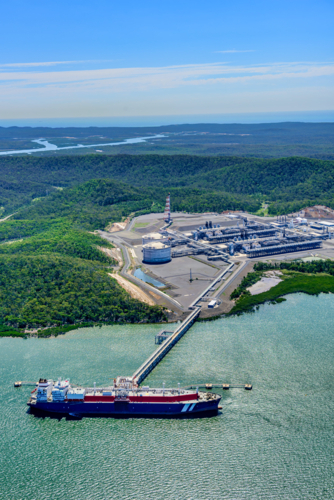 Aerial view of liquified natural gas plant and LNG ship docked at a long pier - Australian Stock Image