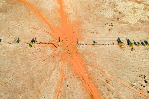 Aerial view of livestock tracks through a gateway in a barren paddock - Australian Stock Image