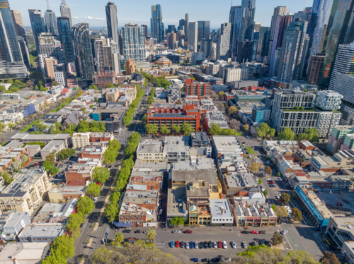 Aerial view of low urban buildings in blocks in front of a highrise city skyline - Australian Stock Image