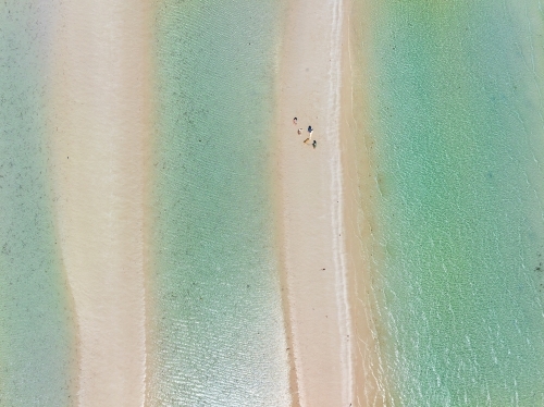 Aerial view of people walking on a narrow sandy  beach between pools of clear water - Australian Stock Image