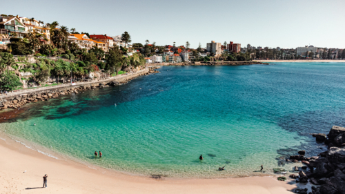 Aerial View of Populated Beach Bay with Clear Blue Water and Coastal Homes - Australian Stock Image