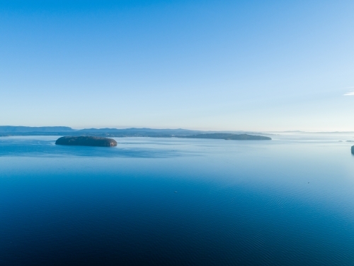 Aerial view of Pulbah Island in blue still water of Lake Macquarie on calm evening - Australian Stock Image