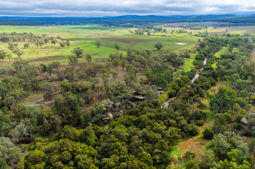 Aerial view of Reedy Creek winding through the granite rock formations and lush green bushland - Australian Stock Image