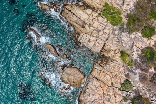 aerial view of Rose Bay in Bowen, Queensland, showcasing turquoise waters and rocky shoreline - Australian Stock Image