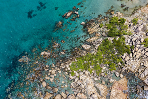 Aerial view of Rose Bay in Bowen, showcasing its rocky shoreline and turquoise waters - Australian Stock Image