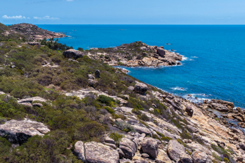 Aerial view of Rose Bay in Bowen, showcasing its shoreline, turquoise waters and rocky headland - Australian Stock Image