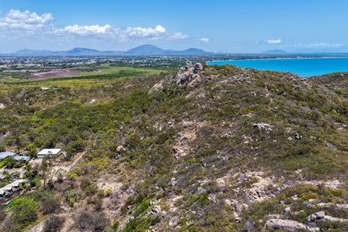 Aerial view of Rose Bay in Bowen, showcasing its shoreline, turquoise waters and rocky landscape - Australian Stock Image