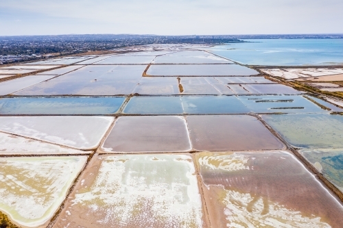 Aerial view of salt evaporation ponds next to a coastal bay. - Australian Stock Image
