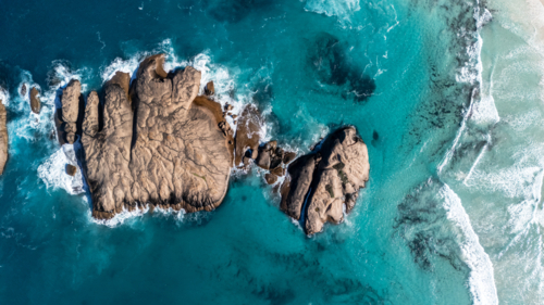 Aerial view of Smooth rounded boulders in a turquoise sea - Australian Stock Image