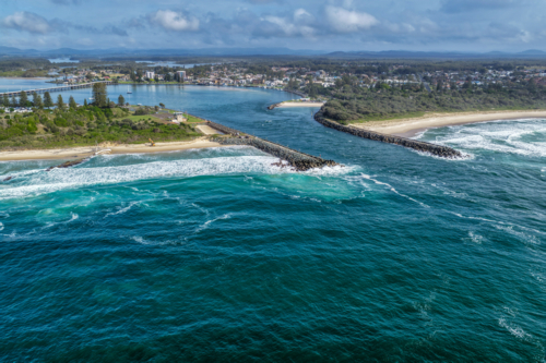 Aerial view of the Forster and Tuncurry breakwalls with the bridge spanning Wallis Lake - Australian Stock Image