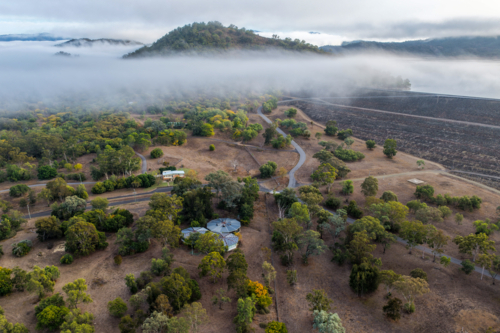 Aerial view of the Glenbawn Dam wall and surrounding landscape with fog rolling through the valley - Australian Stock Image