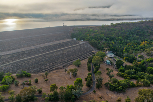 Aerial view of the Glenbawn Dam wall and surrounding landscape with fog rolling through the valley - Australian Stock Image