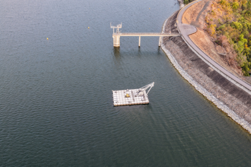 Aerial view of the Glenbawn Dam wall featuring the water intake system and servicing pontoon in NSW - Australian Stock Image