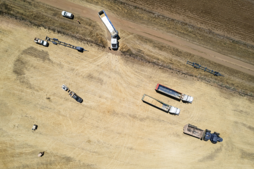Aerial view of transport trucks and combine harvester on the field - Australian Stock Image