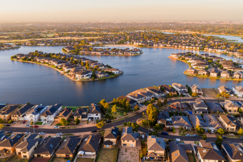 Aerial view of waterfront housing around the shoreline of a lake in late afternoon sunshine - Australian Stock Image